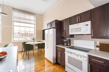 A kitchen with brown cabinets and white appliances and a table with chairs